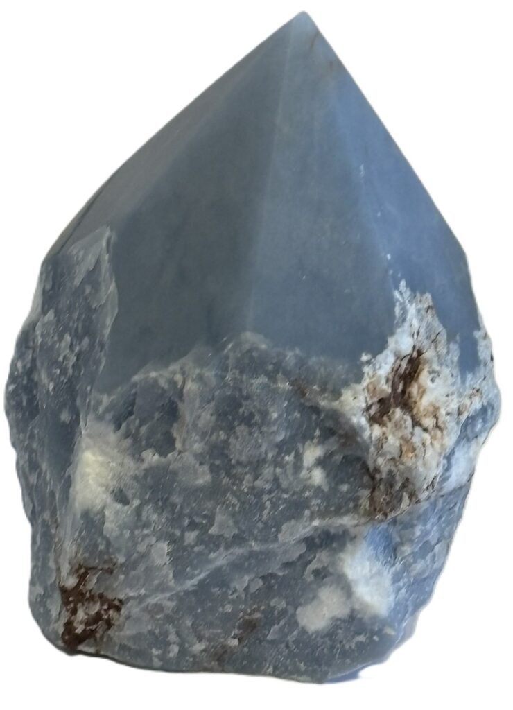 Natural rough angelite freeform with polished point 4 sians emporium Natural rough angelite freeform crystal with unpolished sides and a smooth polished blue point standing on a white background
